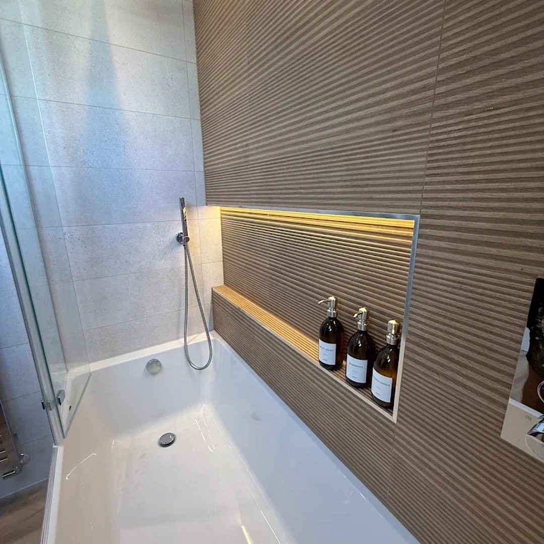 Bath with a rain shower and a lit niche in ribbed wood-effect tiles, fitted by Yorkwood Bathrooms